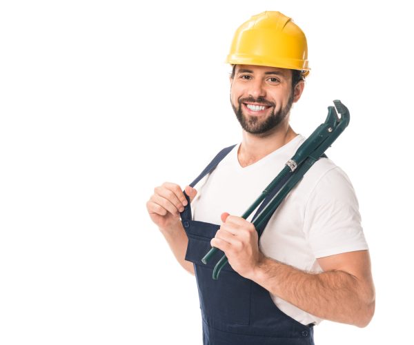 handsome happy workman holding adjustable wrench and smiling at camera isolated on white